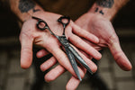 schwarze Friseurschere The Rock aus Edelstahl mit ergonomischem Design und feiner Klingenstruktur in Hand gehalten