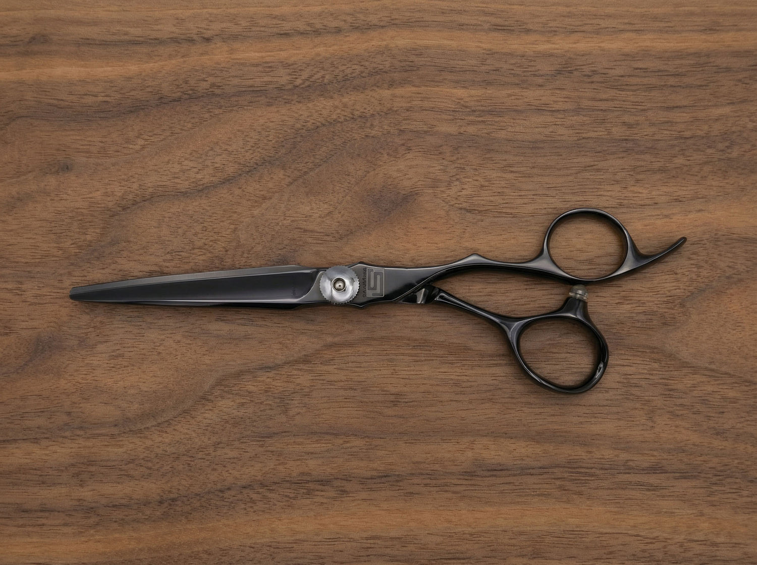 Shidosha Haarschneideschere aus schwarz beschichtetem Stahl mit ergonomischem Griff auf Holzuntergrund