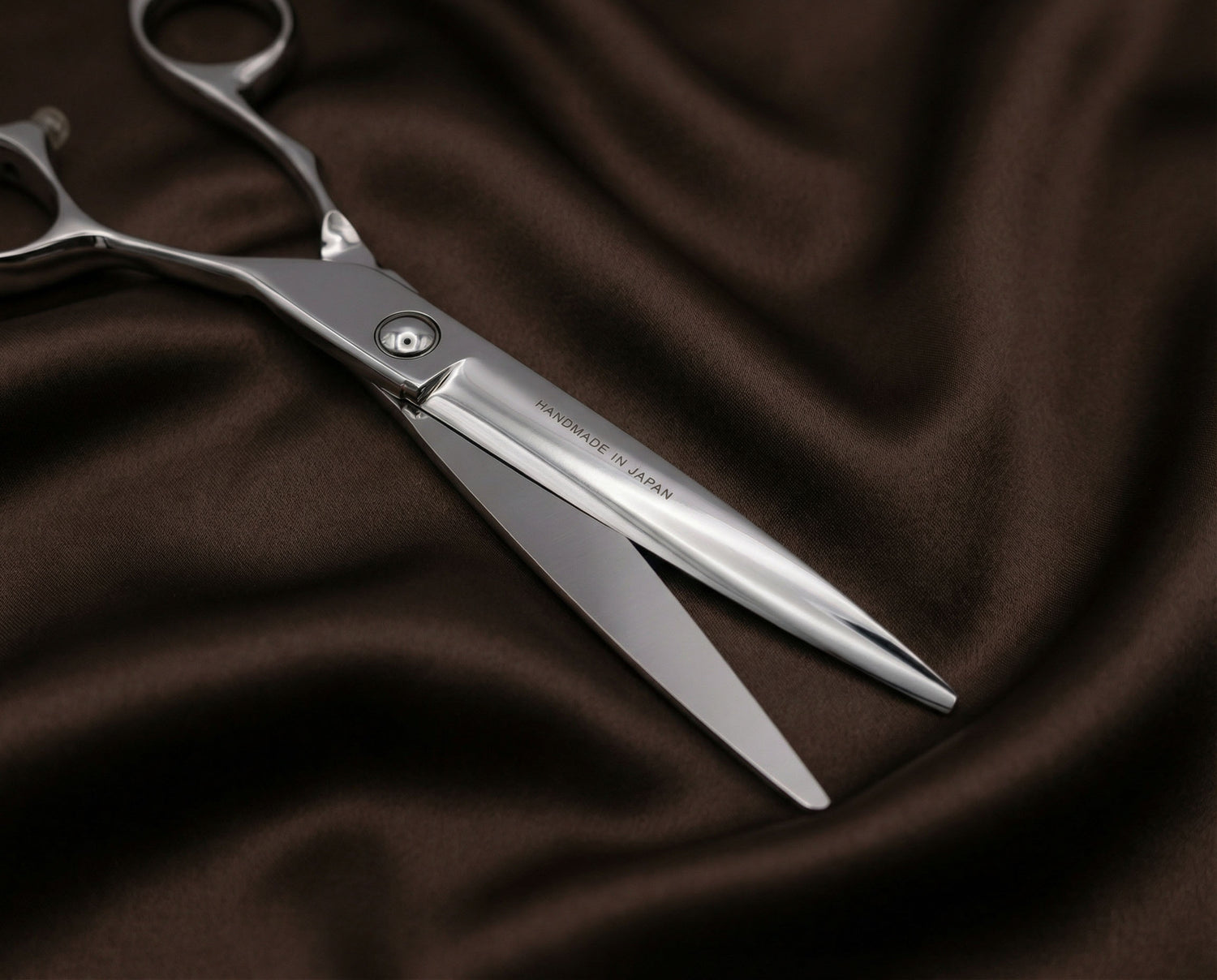 Professionelle Haarschneideschere aus hochwertigem Edelstahl mit ergonomischem Griff auf dunkelbraunem Stoff liegend