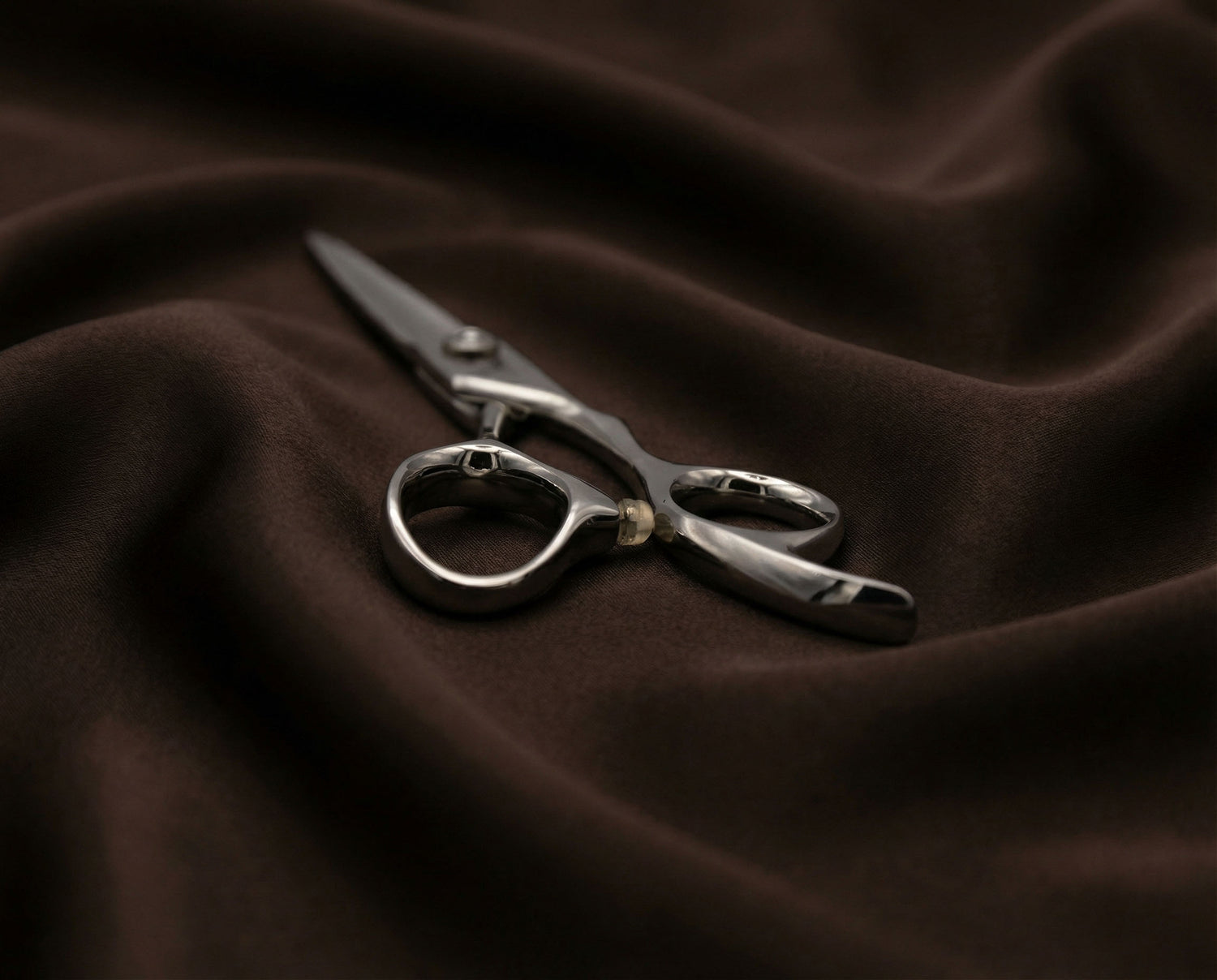 Shidosha Friseurschere aus Edelstahl mit ergonomischem Griff auf dunklem Stoff liegend für professionelle Anwendung