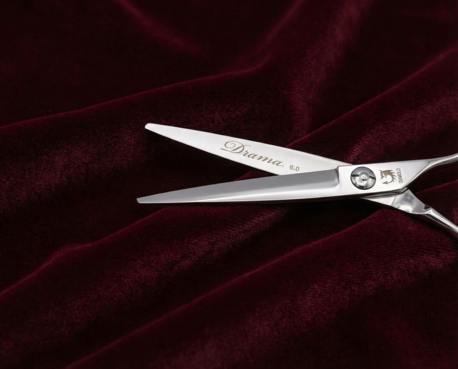 Friseurschere "Drama 6.0" aus Edelstahl mit schlankem Design auf burgunderfarbenem Stoff